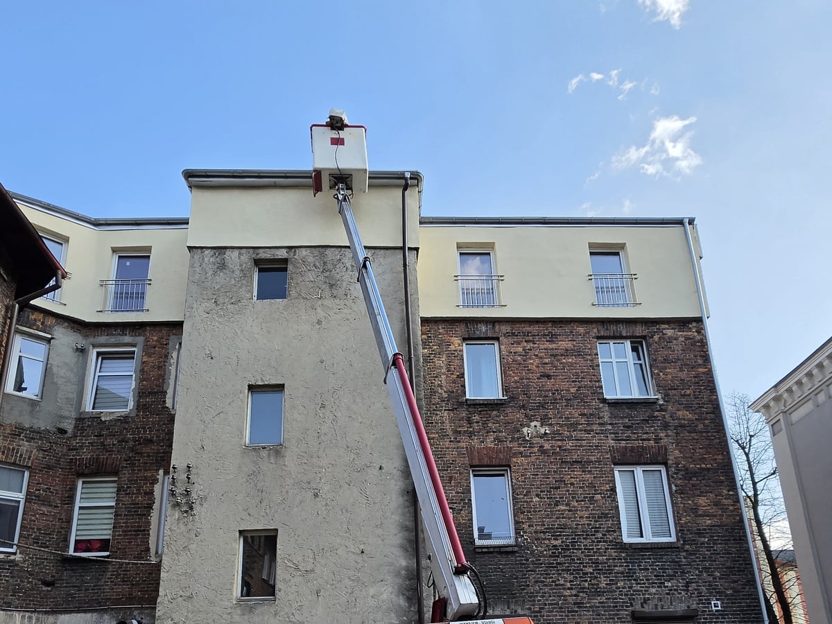 Podnośnik koszowy podczas pracy przy budynku